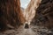 off-road vehicle traveling through narrow canyon, with towering cliffs on either side