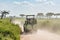 Off-road vehicles moving along dusty road in savannah