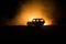 Off roader jeep silhouette on dark toned foggy sky background. Car with light at night.