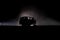Off roader jeep silhouette on dark toned foggy sky background. Car with light at night