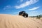 off-roader scaling daunting sand dune under clear blue sky