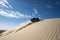 off-roader scaling daunting sand dune under clear blue sky