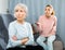 Offended elderly mother listening to reproaches from adult daughter on sofa