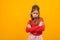 Offended teenager girl crossed her arms on a yellow background with copy space