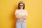Offended unhappy woman wearing striped T-shirt hair band and sunglasses standing isolated over yellow background standing folded