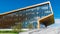 Office building with glass Windows which reflect the floating clouds, along the building there are people. Timelapse