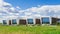 Office building in the meadow with glass windows that reflect the floating clouds, along the building there are people