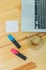 Office desk with accessories: a white sheet of paper, a marker of blue and pink, a gray laptop, a cup of coffee. In