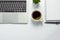 Office desk with coffee cup, blank notebook, black pen, laptop computer and cactus pot