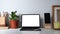 Office desk with computer tablet, smart phone, pencil holder, coffee cup, notebook and plant.