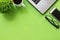 Office desk with green plant, coffee, laptop. smartphone and eyeglasses