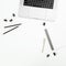 Office desktop workspace with silver laptop, notebook and pen on white background. Top view. Flat lay