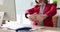 Office employee in pink jacket stretches arms at table to relax