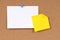 Office index card with post it style yellow sticky note pinned to cork board, copy space