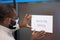 Office opening. Young afro american man in protective face mask sticking open sign with text BACK TO OFFICE on the glass