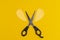 Office stationery scissors and a paper heart cut in half on pure yellow background