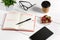 Office table desk with set of supplies, white blank notepad, cup, pen, tablet, glasses, flower on white background. Top