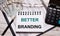 On the office table there is a calculator, a notebook with the text BETTER BRANDING, a pen, glasses and dollars. Stylish workplace