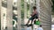 Office window cleaner lowering himself to the ground next to a glass building