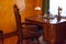 An office with a wooden table and a brown armchair in vintage style. Antique furniture by the window. Historical value