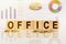 OFFICE the word on wooden cubes, cubes stand on a reflective surface, in the background is a business diagram