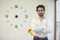 Office worker poses near a clock representing punctuality