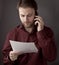 Office worker reading paper documents during mobile phone conversation