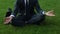 Office worker sits in lotus pose on lawn, distracts from problems, meditation
