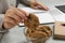 Office worker taking chocolate chip cookie from bowl at light gray table indoors, closeup