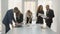 Office workers standing at a square table discuss financial issues of the firm, a young team of three women and two men