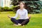 Office yoga. Business lady in lotus pose sits on green grass. Re