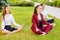 Office yoga. Three young girls in a lotus pose are sitting on gr