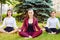 Office yoga. Three young girls in a lotus pose are sitting on gr