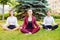Office yoga. Three young girls in a lotus pose are sitting on gr