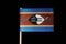 A official flag of Eswatini on toothpick on black background. A horizontal triband of blue and yellow edged red with the large bla