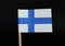A official flag of Finland on toothpick on black background. Consists of Sea-blue Nordic cross on white field