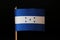 A official flag of Honduras on toothpick and on black background. Honduras is located in central america and belongs to poverty la