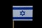 A official flag of Israel on toothpick on black background. A blue Star of David between two horizontal blue stripes on a white