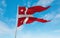 official flag of Naval Rank Senior Officer Afloat, Denmark at cloudy sky background on sunset, panoramic view. Danish travel and