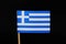 A official and national flag of Greece on toothpick on black background. Nine horizontal stripes, in turn blue and white a white
