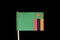 A official, national flag of Zambia on toothpick on black background. Zambia has flag contain eagle and tricolour on green field.