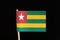 A official and original flag of Togo on toothpick on black background. It has five bands of green alternating with yellow and red
