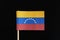 A official and original flag of Venezuela on toothpick on black background. A horizontal tricolor of yellow, blue and red with an