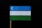 A official and unique flag of Uzbekistan on toothpick on black background. A horizontal blue, white and green stripes.A crescent