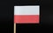 A official and very simple flag of Poland on toothpick on black background. Consists of a horizontal bicolour of white and red