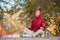 Offline autumn. Adult attractive woman sits on the ground and meditating in urban park outdoor, selective focus.