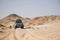 Offroad car in desert landscape bahariya egypt. Low point of view. Car tracks in the sand and volcano hills in the background.