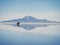 Offroad car SUV jeep of tour group on Salar de Uyuni salt flat lake in Bolivia andes mountains sunrise mirror reflection