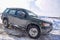 Offroad SUV `Nissan Terrano 4x4` quickly with a spray of Blizzard rides on a snowy road in winter