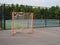 Offseason, beat up, rusted, ragged lacrosse goal sitting on asphalt court with nets tearing